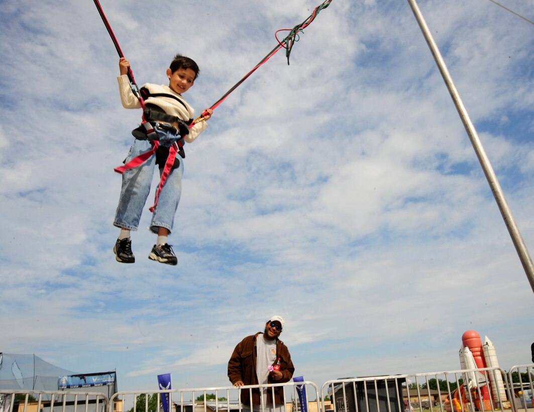 Joint Base Andrews, Md.- Ethan Ali, 7-years-old, reverse bungee jumps as his father, Daniel Ali, cheers him on during Joint Service Open House here May 16. The reverse bungee jump is one of many activities offered in the Kid Zone. JSOH offers interaction for all members of the joint service community and the public. (U.S. Air Force photo by Staff Sgt Keyonna Fennell)