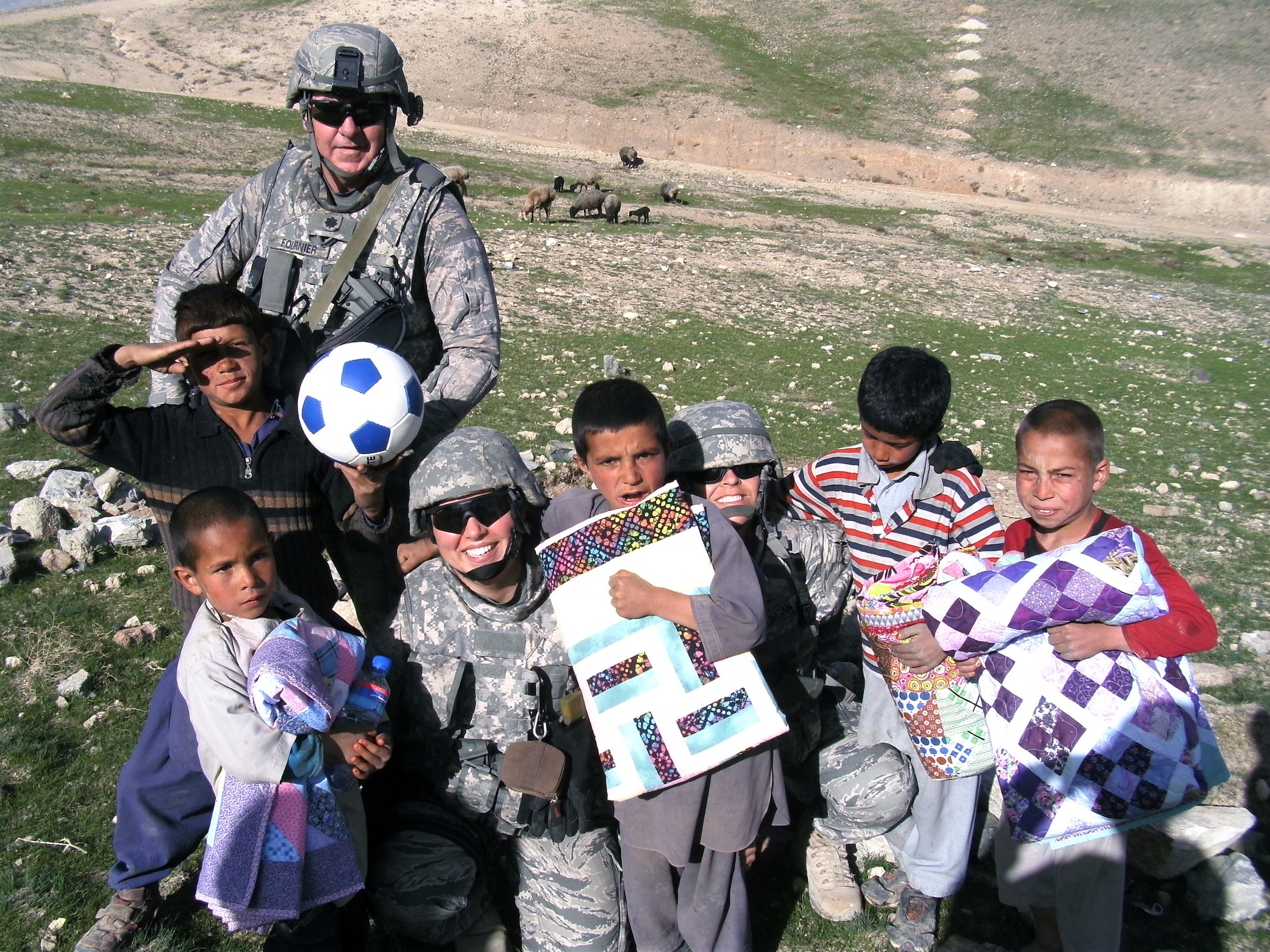 Airmen assigned to the 855th Air Expeditionary Squadton take time to pose with Afghan children during a "Quilts for Kids," humanitarian mission in Regional Command East, Afghanistan. The 855th AES has more than 850 joint expeditionary tasked Airmen who work with local provincial reconstruction, agricultural development and mentoring teams throughout eastern Afghanistan (Courtesy photo)           