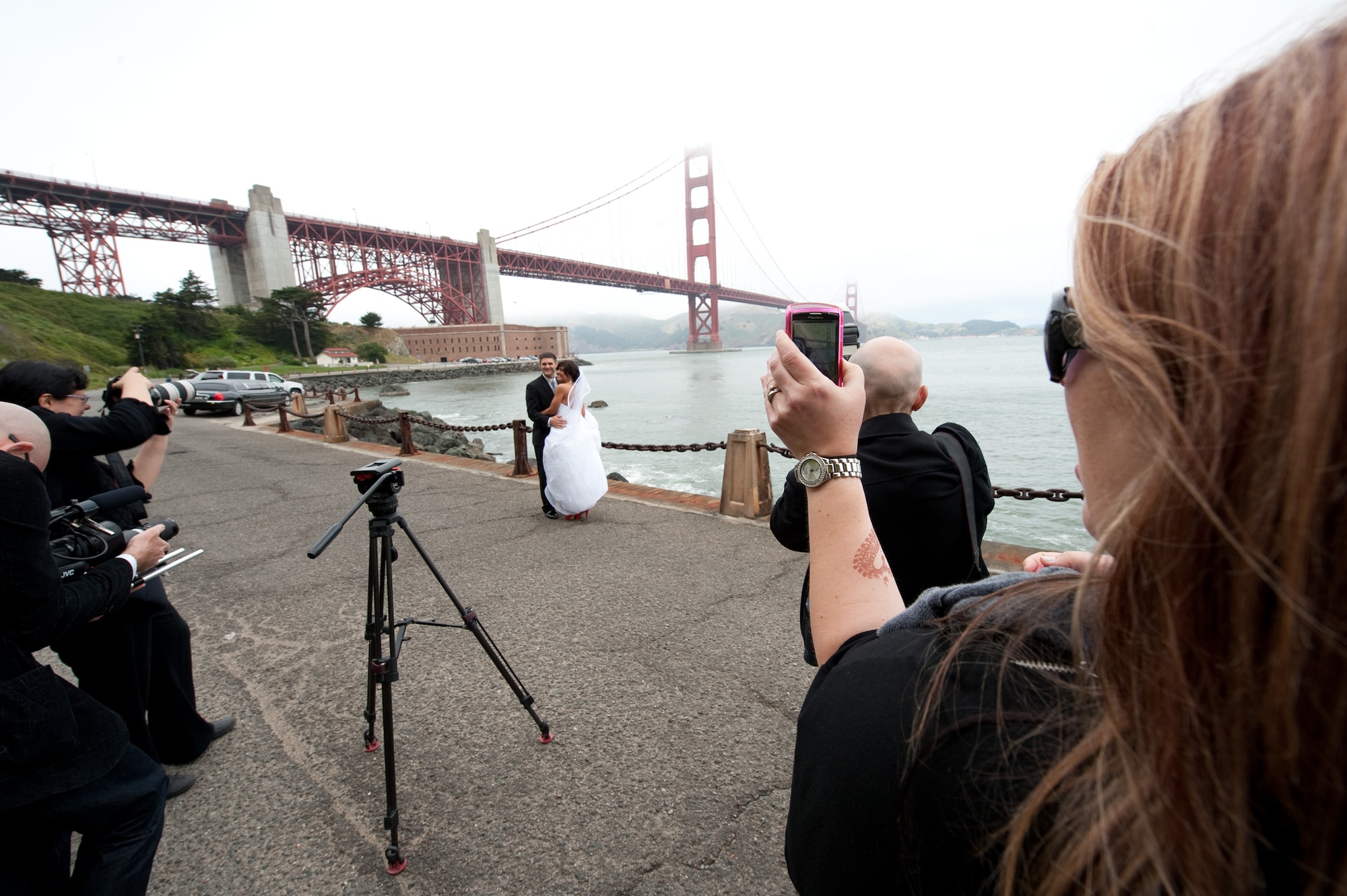 Amy Frugoli (right), wedding planner, snaps some production photos during the wedding day of Vanessa Muza Teskey and Capt. Mike Hawkins. The wedding couple were brought to Fort Point, the classic and foggy wedding photo site near the southern anchorage of the Golden Gate Bridge in San Francisco May 14, 2010. The couple and a multimedia team were whisked by limousine to several photo locations. The two won the San Francisco Dream Wedding Giveaway with viewer votes. Mrs. Hawkins has been diagnosed with stage IV Hodgkin's lymphoma. Vendors donated $100,000 of goods and services to the couple's wedding day. (U.S. Air Force photo/Lance Cheung)