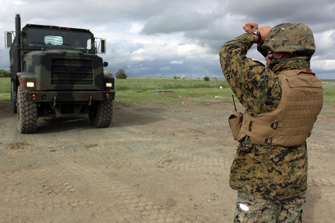 Cpl. Michael Seto, an ammunition technician with Headquarters and Service Company, 1st Tank Battalion, and native of Meridian, Miss., ground guides Lance Cpl. Jesse Watson, an assault man with H and S Co., 1st Tank Bn., and Louisville, Ky., native, after arriving at Babadag Training Area, Romania.