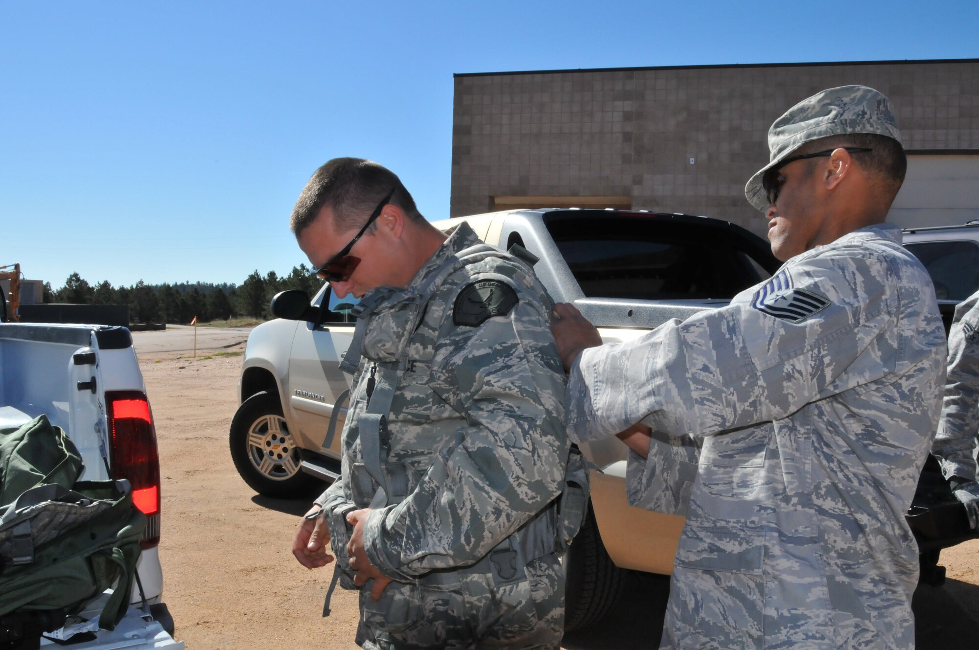Officer Steven Haymes from the Space and Missile Systems Center's 61st Security Forces Squadron puts on his utility belt with Tech. Sgt. Leslee Williams' assistance in preparation for the marksmanship competition at Guardian Challenge 2010 May 17. (Photo by Lou Hernandez)