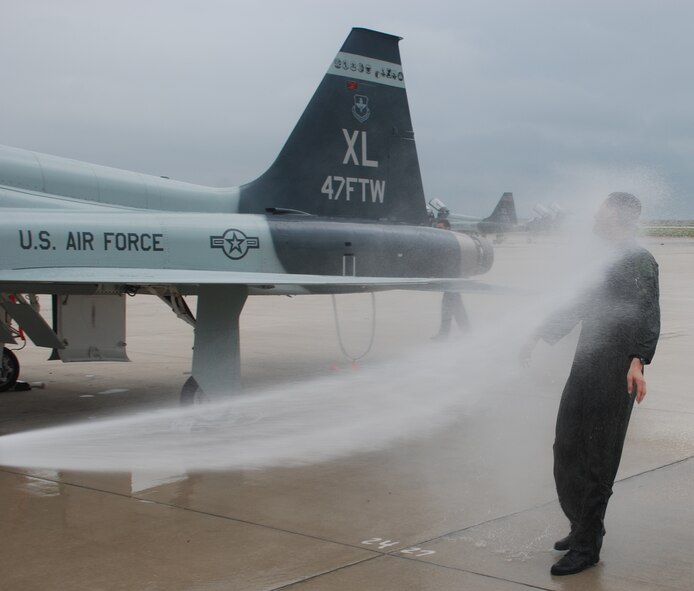 LAUGHLIN AIR FORCE BASE, Texas – Col. Jeffrey McDaniels, 47th Flying Training Wing commander, is drenched with a fire hose by his wife just after completing his final flight as wing commander. As is tradition for outgoing commanders, Colonel McDaniels taxied through an arch of water supplied by Laughlin’s fire department after landing. (U.S. Air Force photo by Airman 1st Class Blake Mize)