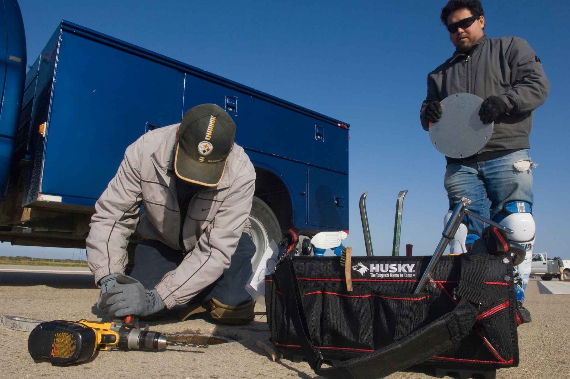 VANDENBERG AIR FORCE BASE, Calif. - Mr. Stephen Todd, of the 30th Civil Engineer Squadron, scrapes a seal from a runway light hole while Mr. Johnny Tucker, also from the 30th CES, brings him a new metal plate to cover the hole on the flightline here Saturday, May 8, 2010. Construction crews replaced the metal plates to ensure the X-37B has a safe landing. (U.S. Air Force photo by Staff Sgt. Levi Riendeau)
