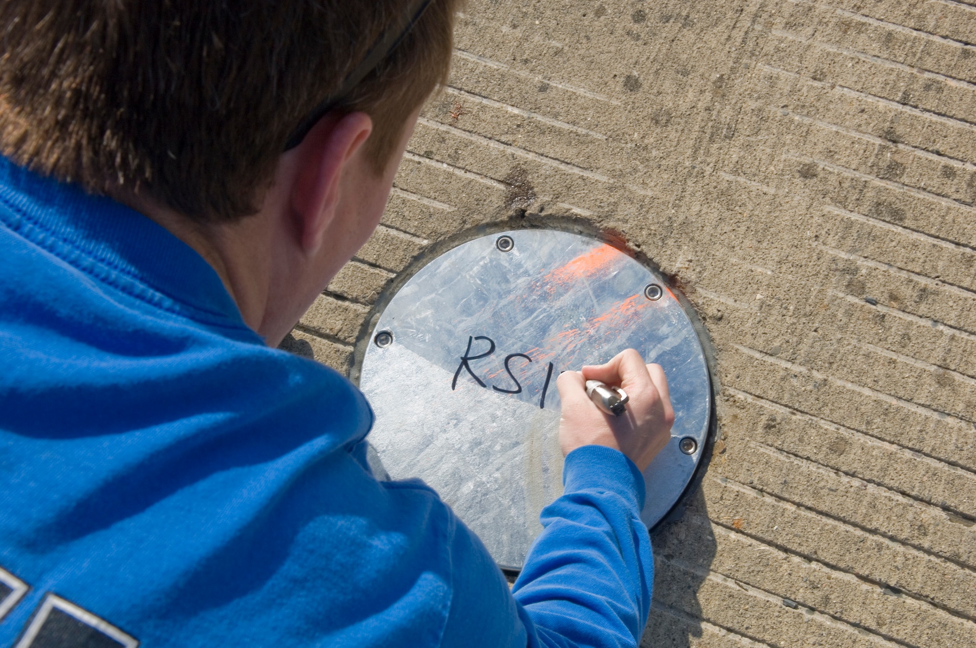 VANDENBERG AIR FORCE BASE, Calif. -- 2nd Lt. Mike Kelly, of the 30th Civil Engineer Squadron, signs a metal plate to signify it has passed inspection during installation on the flightline at here Saturday, May 8, 2010. Construction crews replaced the metal plates to ensure the X-37B has a safe landing. (U.S. Air Force photo by Staff Sgt. Levi Riendeau)
