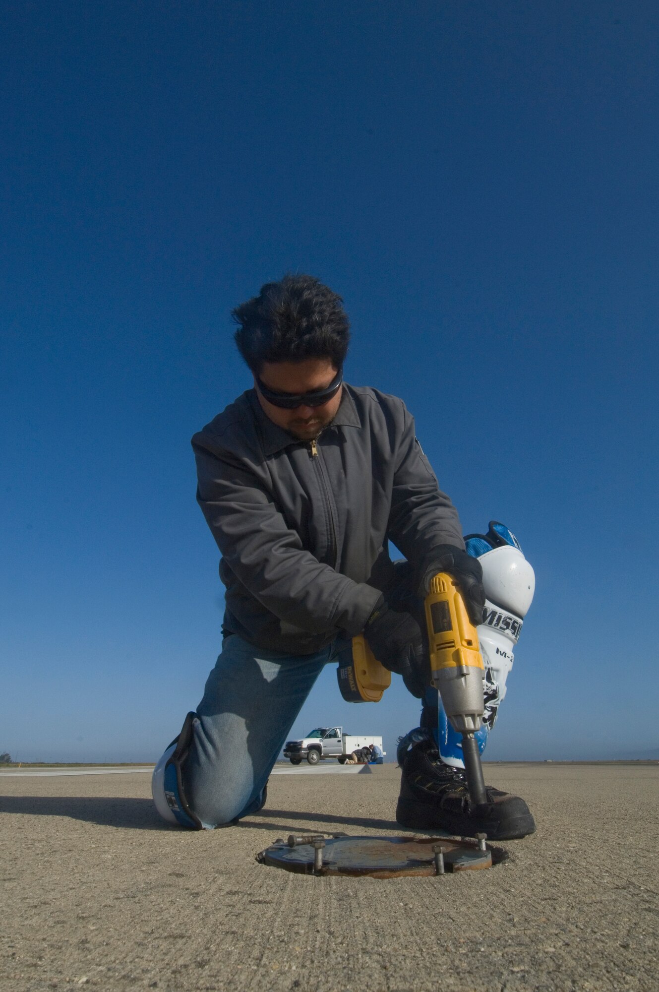 VANDENBERG AIR FORCE BASE, Calif. - Mr. Johnny Tucker, of the 30th Civil Engineer Squadron, removes bolts from the metal plates on the flightline here Saturday, May 8, 2010. The metal plates needed to be replaced to provide a smooth landing for the X-37B. (U. S. Air Force photo by Staff Sgt. Levi Riendeau)
