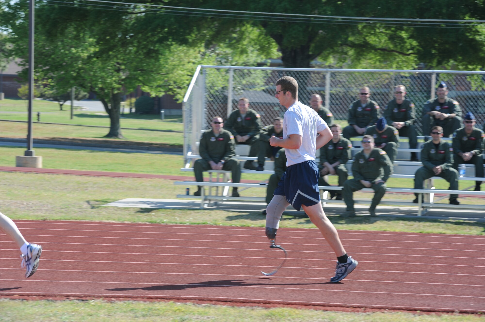 Senior Airman Brian Petras runs past fellow wingmen as they shout out their encouragement and support during his physical fitness test April 15, 2010. Airman Petras, diagnosed with cancer in 2009, passed his physical fitness test and returned to duty less than a year after surgery to remove part of his right leg. He is a flight engineer with the 50th Airlift Squadron at Little Rock Air Force Base, Ark. (U.S. Air Force photo/Staff Sgt. Chad Chisholm)