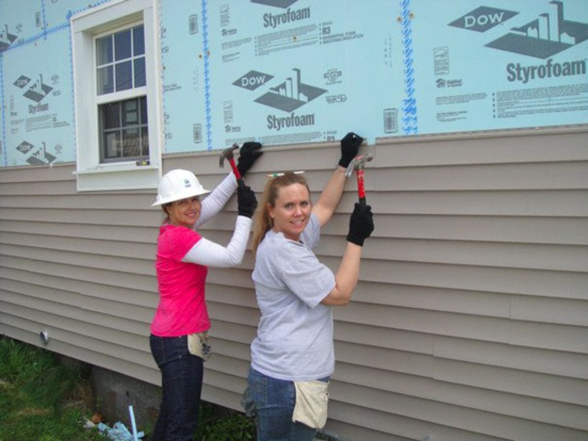 Master Sgt. Wendy Born and Master Sgt. Amy Granfors, 399th Recruiting Service, hang vinyl siding on a Habitat for Humanity house in Battle Creek, Mich. Members of the 339th Recruiting Squadron donated 40 hours of "sweat equity" to Amber, the future home owner. The recruiting team installed vinyl siding, constructed a new porch and reinforced an existing porch for this Habitat for Humanity home. (Courtsey photo)