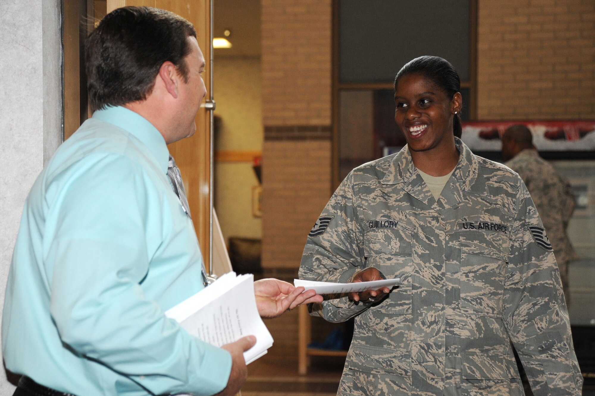 Gregory Diehl, 22nd Force Support Squadron educations specialist, hands Tech. Sgt. Ekesha Guillory, 22nd Maintenance Group NCOIC knowledge operations management, a program during the Community College of the Air Force graduation April 14, 2010, McConnell Air Force Base, Kan.  More than 300 Team McConnell members attended the graduation for more than 50 graduates.  The Community College of the Air Force was started in 1977 and is dedicated to the enlisted members of the Air Force.  On May 5, 2010, the Community College of the Air Force recognized its 350,000th degree recipient during the 2010 Senior Enlisted Leader Summit at the Senior NCO Academy, Gunter Annex, Ala. (U.S. Air Force photo/Tech. Sgt. Chyrece Campbell)