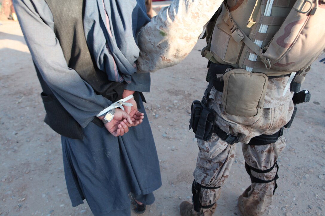 An Afghan Counter Narcotic National policeman holds the Afghan government’s primary drug kingpin in Marjah, Afghanistan May 18. The mission, a team effort between the Marines, Drug Enforcement Administration and Counter Narcotic Police of Afghanistan, nabbed high-level drug traffickers.::r::::n::