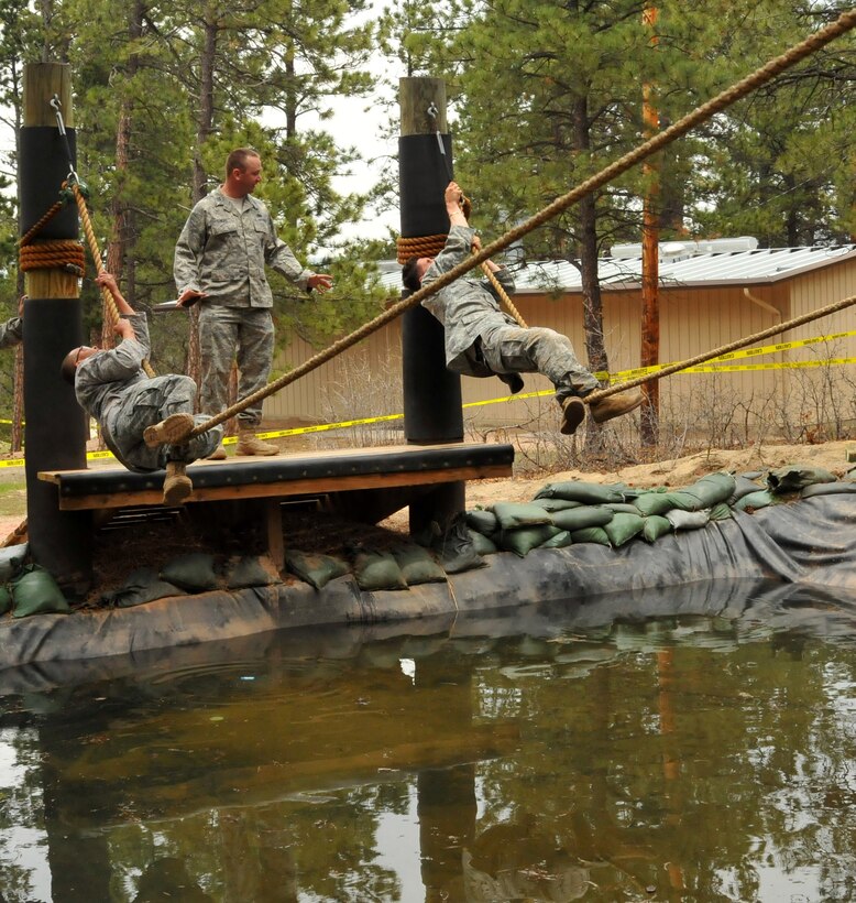 Tech. Sgt. Leslee Williams (left) goes hand over hand on the rope while hanging over water at the Assault Course as Staff Sgt. Alex Andriyanov (right) reaches the end of his rope during a practice run on the Assault Course at the U.S. Air Force Academy, Colo., May 18, 2010. Both are Guardian Challenge 2010 competitors from the Space and Missile Systems Center's 61st Security Forces Squadron at Los Angeles Air Force Base. (Photo by Lou Hernandez)