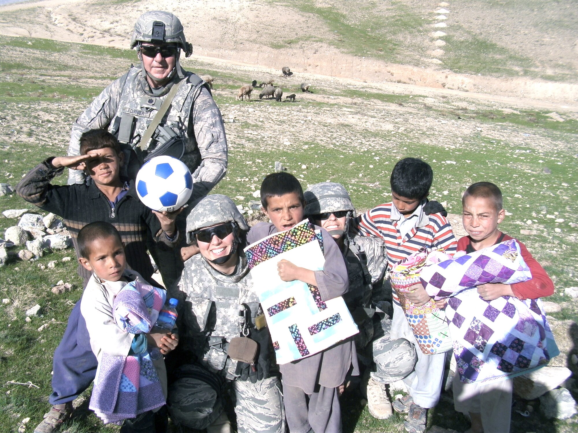 Airmen assigned to the 855th Air Expeditionary Squadron take time May 10, 2010, to pose with Afghan children during "Quilts for Kids," a humanitarian mission in Regional Command East, Afghanistan. The 855th AES has more than 850 joint expeditionary tasked Airmen who work with local provincial reconstruction, agricultural development and mentoring teams throughout eastern Afghanistan. (U.S. Air Force photo)