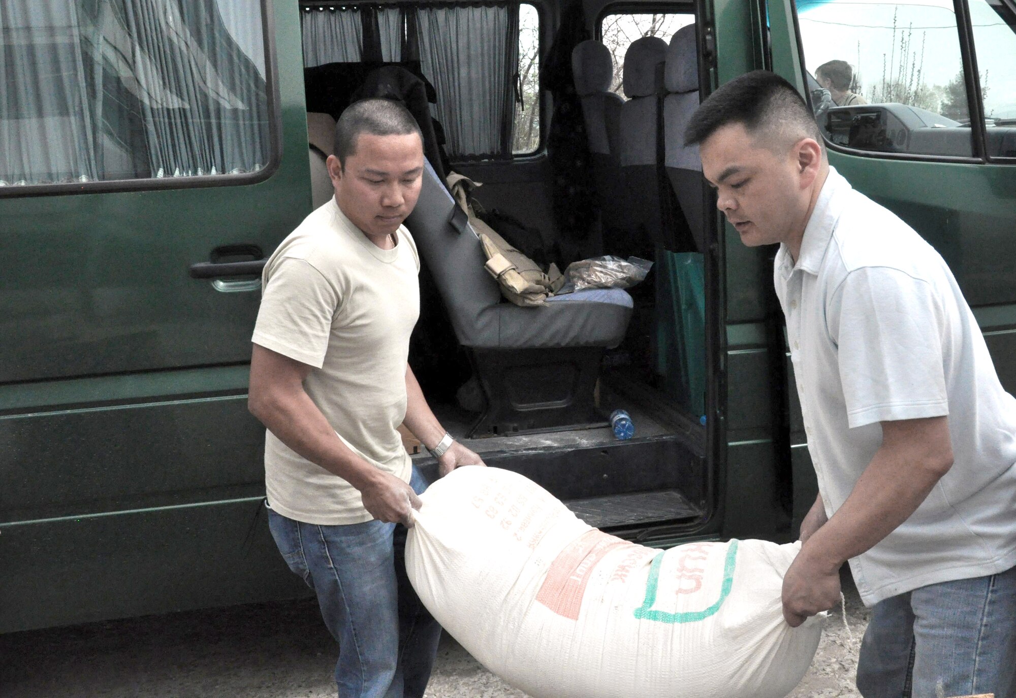 Staff Sgt. Jeff Legaspi (left) and Capt. Tom Mulka carry a 100-pound bag of flour into the TokMok Psychoneurologic Boarding House in Iskra Village, Kyrgyzstan.  Donating food is just one of the many humanitarian assistance projects carried out by Airmen at the Transit Center at Manas, Kyrgyzstan.  (U.S. Air Force photo/Staff Sgt. Carolyn Viss)