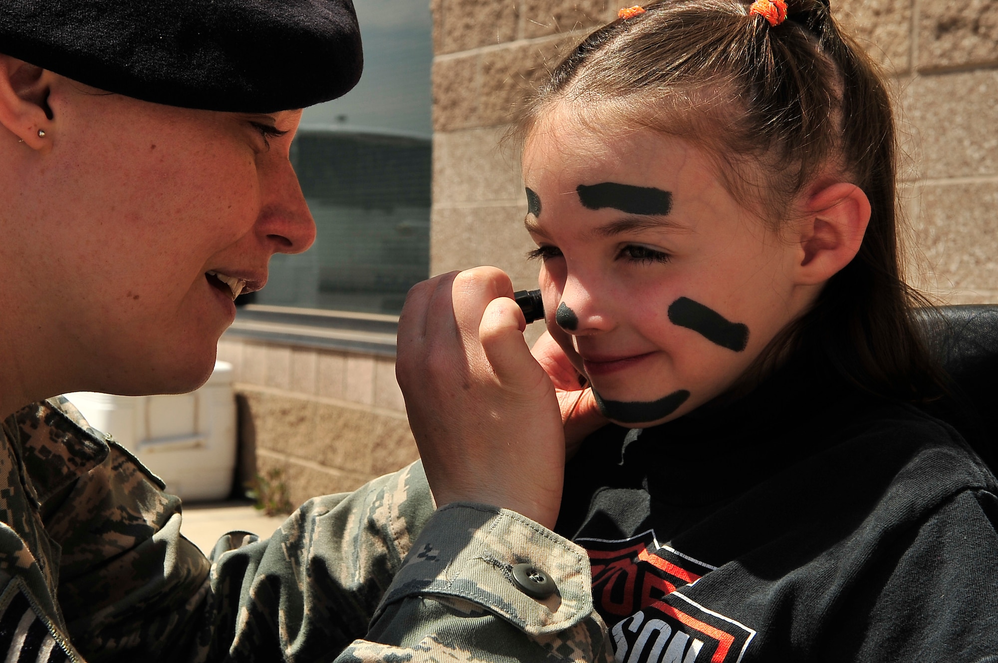 BUCKLEY AIR FORCE BASE, Colo. -- Elizabeth Noethlich, daughter of Summer Noethlich, gets her face painted by Staff Sgt. Nichole Gladkowski, 460th Security Forces Squadron, during National Police Week, May 14. National Police Week falls on the week of May 15, Peace Officers Memorial Day. National Police Week is a time to honor fallen defenders and for many police-to-community outreach programs. (U.S. Air Force photo by Staff Sgt. Kathrine McDowell)