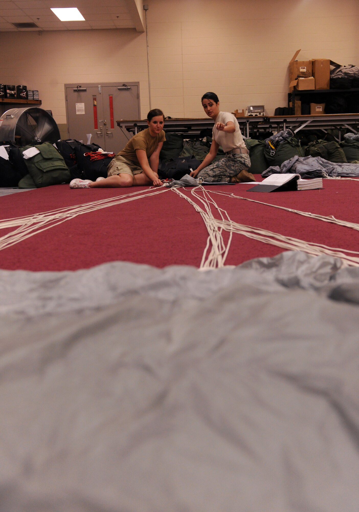 Senior Airman Andrea Brandenberg trains Airman 1st Class Caitlan Bunn on how to properly pack a free-fall parachute May 10, 2010, at Moody Air Force Base, Ga. Airman Brandenberg is a 38th Rescue Squadron logistics flight aircrew flight equipment journeyman. Airman Bunn is a 38th RQS AFE apprentice. Airmen Brandenberg and Bunn are just two of the more than 10 Airmen who pack parachutes for the 38th RQS. (U.S. Air Force photo/Airman 1st Class Benjamin Wiseman)