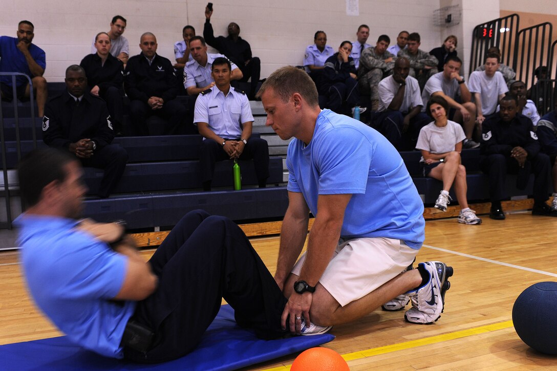 LANGLEY AIR FORCE BASE, Va. -- Tony Arroyo and Chris Bendix, 633d Force Support Squadron fitness testing technicians, demonstrate the proper crunch during the fitness assessment demonstration May 17. The demonstration is designed to prepare personnel for the transition to Fitness Assessment Cell testing in July. (U.S. Air Force Photo/Staff Sgt. Christina M. Styer) 