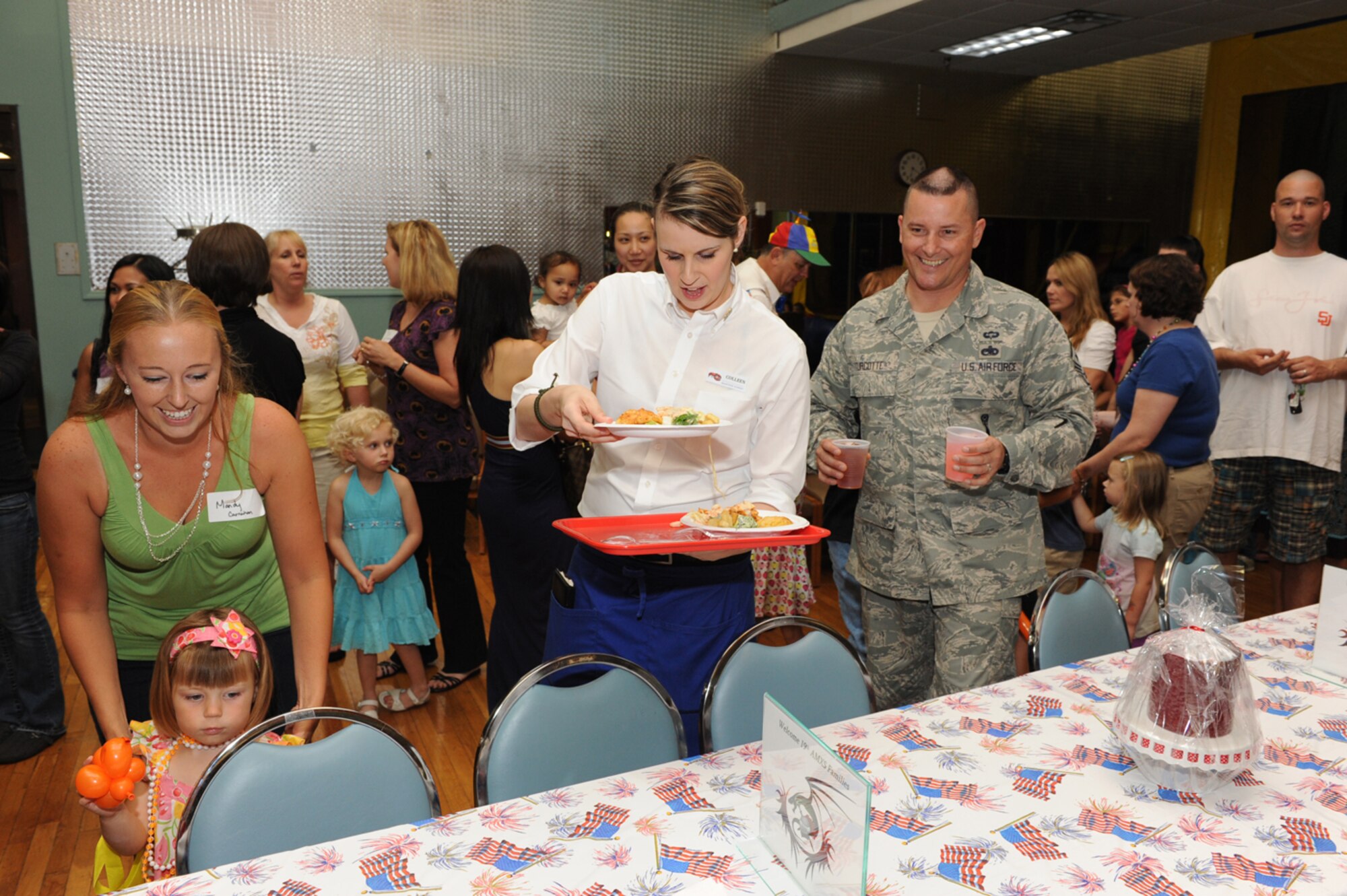 Chief Master Sgt. Richard Turcotte, 314th Airlift Wing command chief, carries drinks for Mandy Carnahan, wife of Tech. Sgt. Michael Carnahan, 19th Aircraft Maintenance Squadron, and daughter, Ally, as a Red Lobster seafood expert serves their food May 11 at the Deployed Families’ Dinner. The event is one way the base brings together families of Team Little Rock deployed members. (Photo by Senior Airman Ethan Morgan)