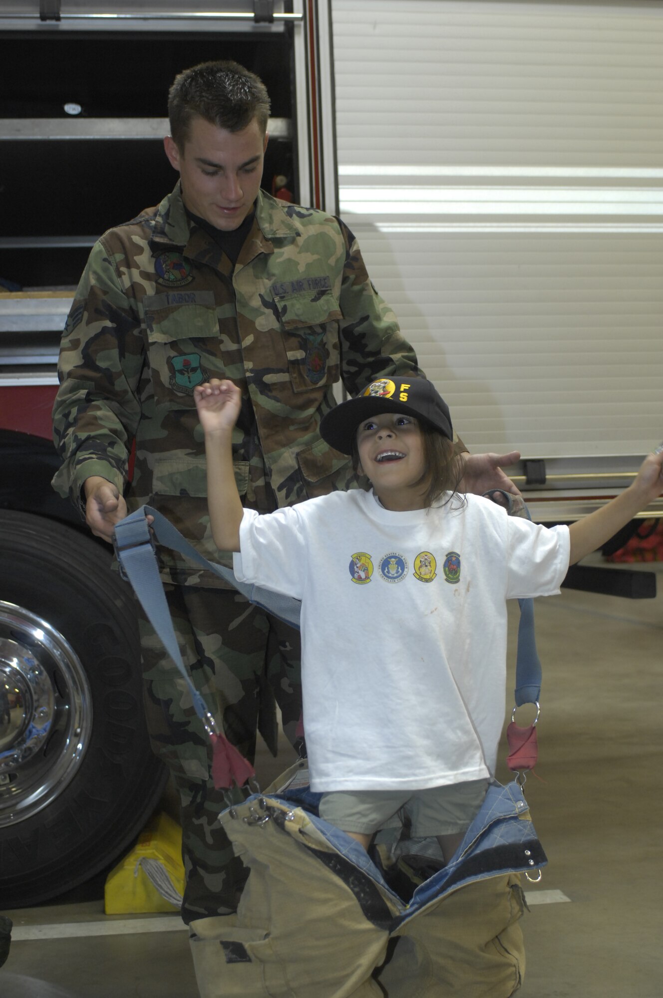 Jessica Ruiz, 4, is helped by Senior Airman Justin Tabor, 56th Civil Engineer Squadron Fire Fighter engine driver, into fire fighting gear, Luke Air Force Base, Ariz., May 14, 2010.  Jessica was one of 12 children from the Childrens Crisis Nursery to tour Luke. The visit included walking on the flight line to see an F-16 Fighting Falcon, eating at the Dining Facility, viewing a military working dog demonstration and manning a water hose at the base fire station. (U.S. Air Force Photo by Staff Sgt. Jason Colbert)