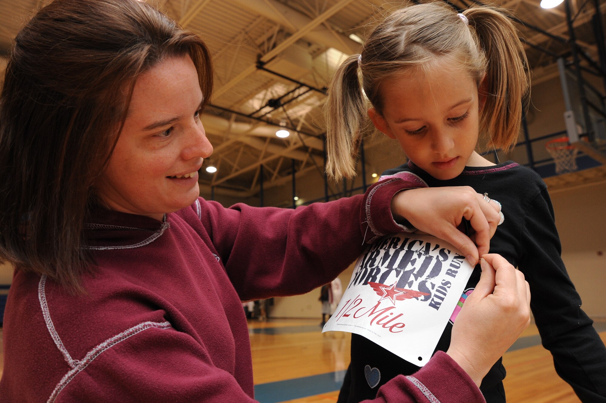 Tosha Stalter, Team McConnell family member, pins a runners registration sign on her daughter, Lana, 6, during the America’s Kids Run, May 15, 2010, at the fitness center, McConnell Air Force Base, Kan.  Lana ran the 1/2 mile event helping McConnell’s youth earn a total of 23 miles.  Military family members in the United States and aboard participate in the America's Kids Run in conjunction with Armed Forces Day activities in May each year.  McConnell’s youth program, which supports more than 2,150 children, organized the base event. (U.S. Air Force photo/Tech. Sgt. Chyrece Campbell)