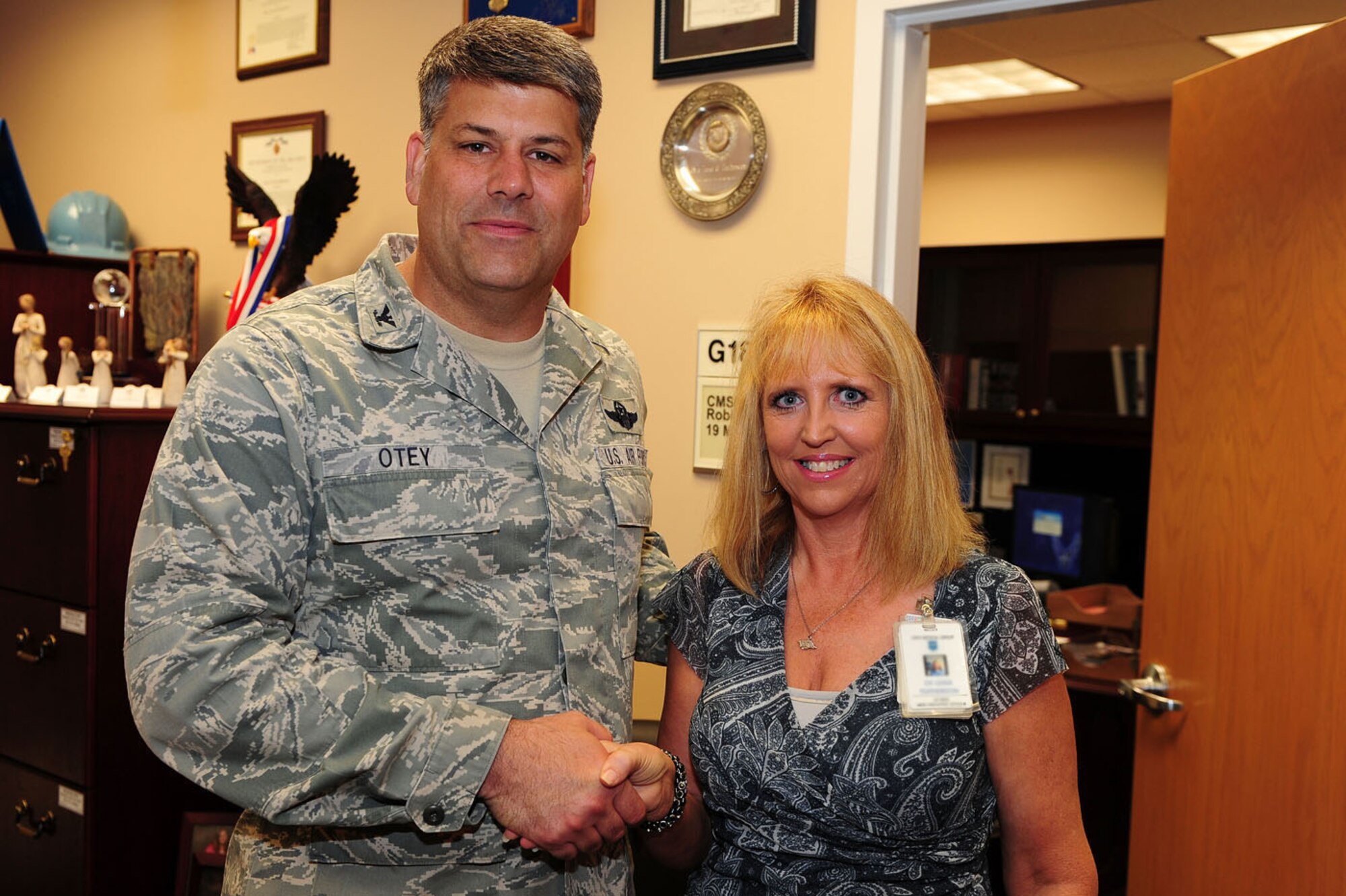 Col. Greg Otey, 19th Airlift Wing commander, presents Ms. Leasa Featherston, 19th Medical Group secretary and executive officer, with a commander’s coin May 18 for her selection as Combat Airlifter of the week. Her commander called her an “extremely hard working individual who is the ‘glue’ that holds the 19th MDG command section together.” Her accomplishments include authoring and editing more than 20 articles for publication in the base’s medical guide and being a strong patient advocate. (Photo by Senior Airman Steele C.G. Britton)