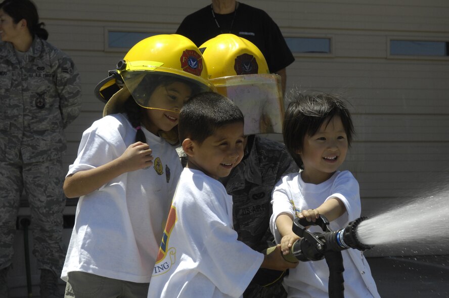 Jessica Ruiz, 4, Carlos Ruiz, 3, and Vivian Chang, 3, help Staff Sgt. Hunter Howe, 56th Civil Engineer Squadron lead fire fighter, aim a fire hose while visiting the a fire station, Luke Air Force Base, Ariz., May 14, 2010. Twelve children from the Childrens Crisis Nursery visited Luke; the tour included checking out the flight line to see an F-16 Fighting Falcon, eating at the Dining Facility as well as seeing one of the base fire stations. (U.S. Air Force Photo by Staff Sgt. Jason Colbert)