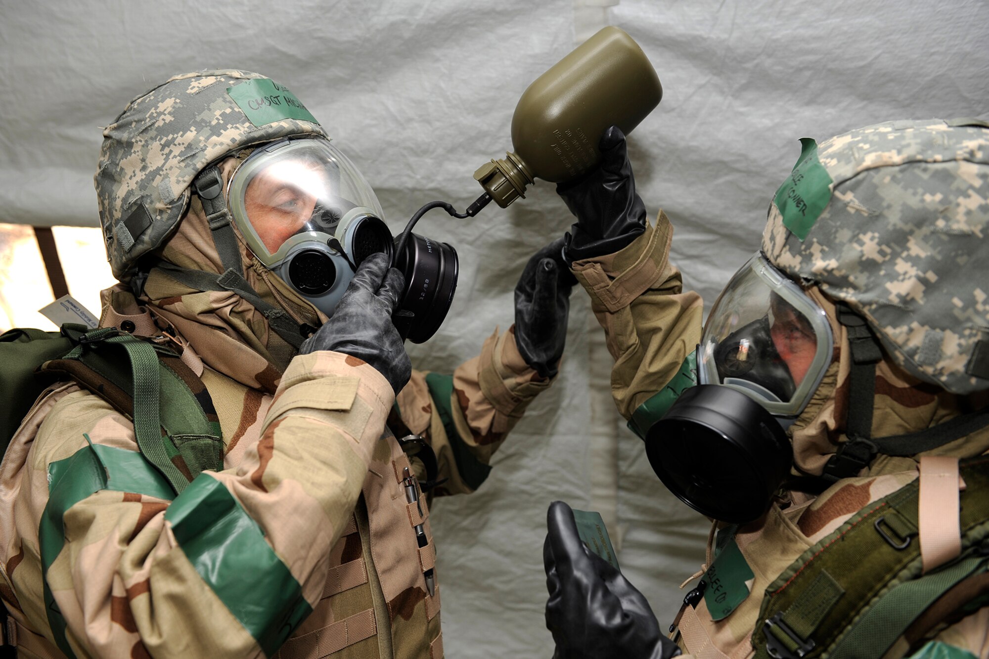PETERSON AIR FORCE BASE, Colo. -- Col. Kimerlee Conner, 21st Mission Support Group commander (right), assists Chief Master Sgt. Michael Hayter, 21st MSG first sergeant, as he drinks water from a canteen using his gas mask drinking apparatus on May 7. This is one of many tasks evaluated during the quarterly exercise Condor Crest. This exercise was designed to test the wing’s ability to perform deployment and field operations and how to survive in a chemical environment. (U.S. Air Force photo/Craig Denton)