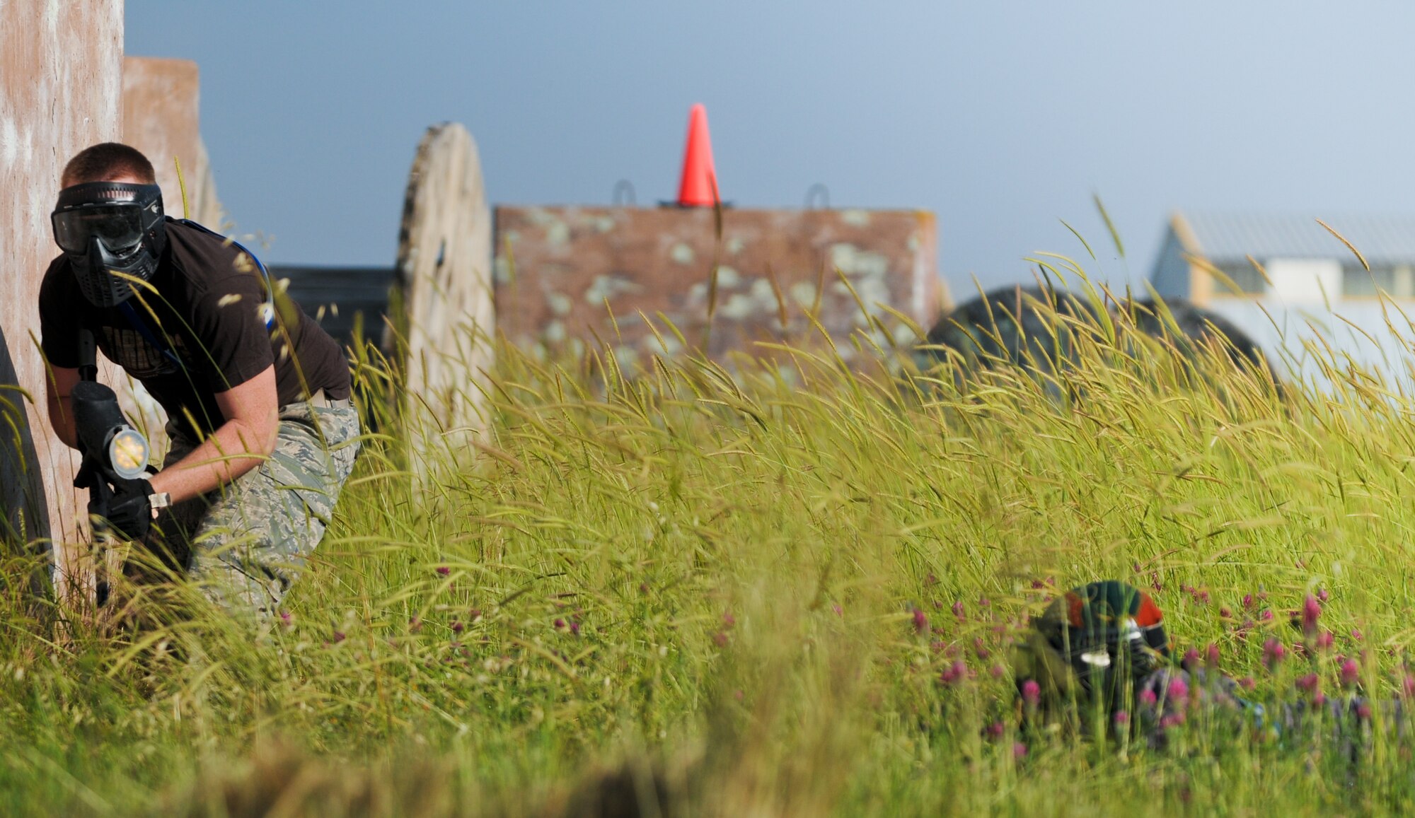 An Airman from the 39th Security Forces Squadron hides behind a wall during a Police Week paintball tournament, while a member from the opposing team sneaks through the grass behind him, Thursday, May 13, 2010 at Incirlik Air Base, Turkey. (U.S. Air Force photo/Senior Airman Sara Csurilla)