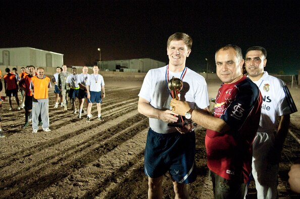 U.S. Air Force Col. Eric Nelson, 321st Air Expeditionary Wing, Iraq Training Advisory Mission-Air Force, surgeon accepts the third place trophy given by Iraqi Air Force Brig. Gen. Mohamed, deputy commander, New Al Muthana Air Base, Iraq during a late-night football (soccer) tournament  at NAMAB, May 17, 2010. The tournament promotes camaraderie, sportsmanship and building partnerships among coalition forces. (U.S. Air Force photo by Senior Master Sgt. Elizabeth Gilbert/released) 