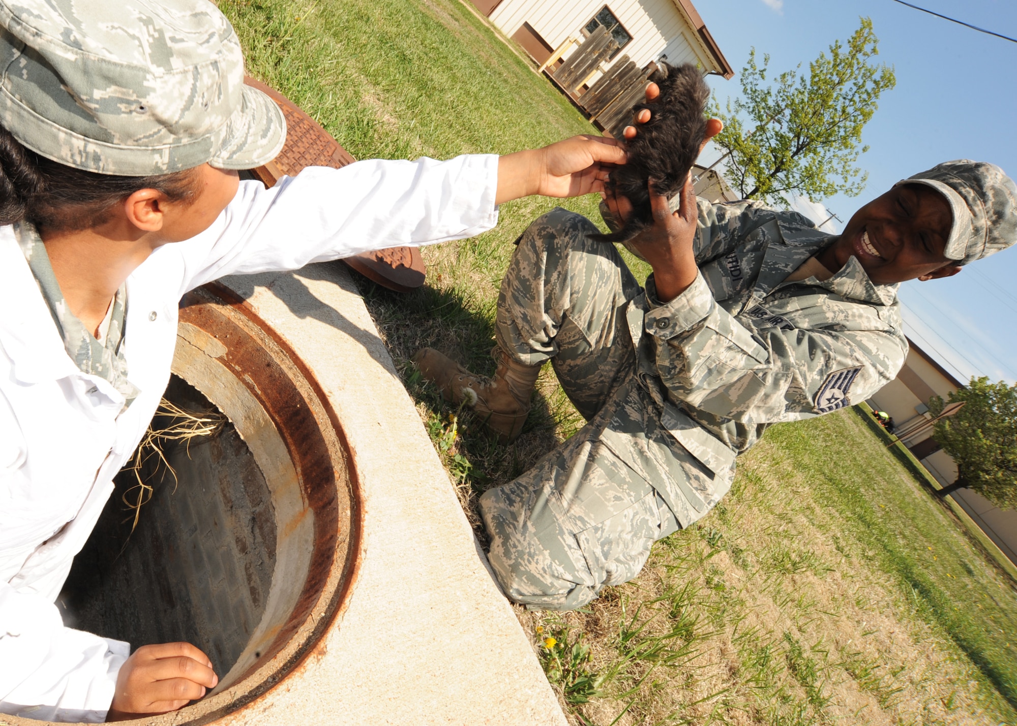Airman 1st Class Cherleen Glass, 22nd Civil Engineer Squadron pest management apprentice, safely hands a rescued 2-week-old kitten to Staff Sgt. Kahlila Mutidi, 22nd CES pest management journeyman, April 14, 2010, McConnell Air Force Base, Kan.  One of the responsibilities of the pest management office is to manage stray animals found at McConnell.  If the owner of a stray animal cannot be found, the animal is transported to the Wichita Humane Society. (U.S. Air Force photo/Senior Airman Maria Ruiz)