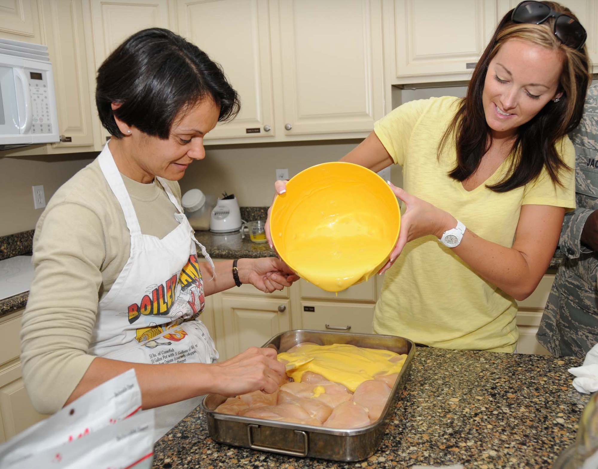 Tech. Sgt. Amanda Fish, 81st Medical Operations Squadron, and Staff Sgt. Jacqueliine Pena, 334th Training Squadron, prepare a baked chicken dish for guests at Fisher House May 13.  The dinner was prepared by members of the Air Force Sergeants Association Chapter 652.  Keesler’s Fisher House provides a home-away-from-home for the families of patients seeking treatment at the 81st Medical Group Hospital or the Veterans Affairs Medical Center in Biloxi.  Keesler’s facility is one of 45 Fisher Houses located on 18 military installations and 15 VA medical centers.(U.S. Air Force photo by Kemberly Groue)