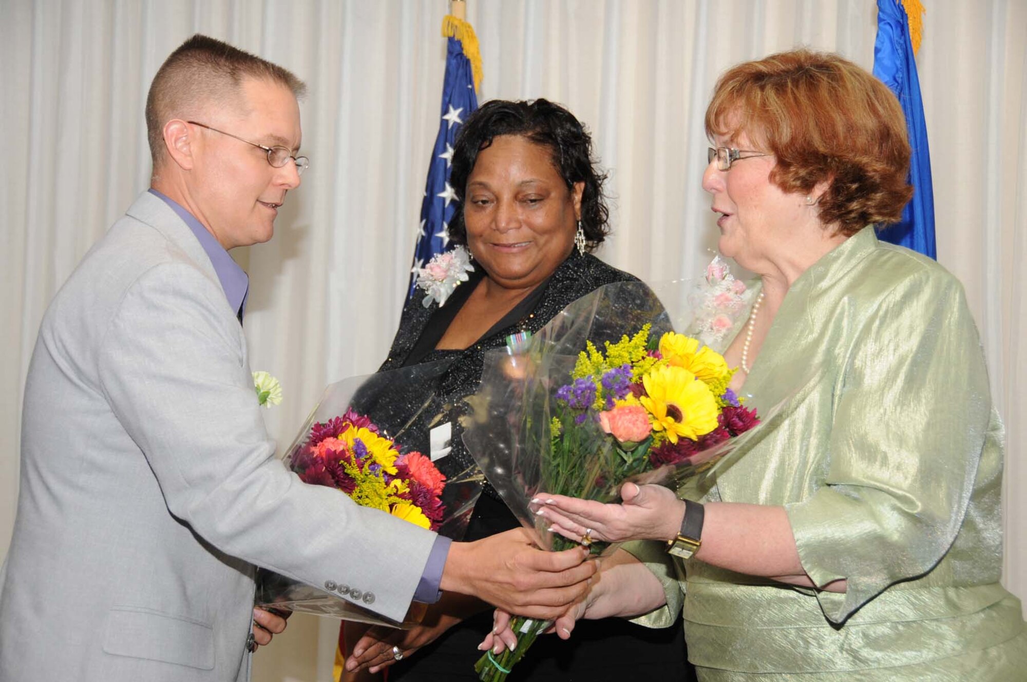 From left, Lt. Col. Richard Cole, 81st Force Support Squadron commander, presents bouquets to Roveta Simmons, child development center director, and Cherrie Tiggeman, flight chief for the CDC and youth center, at a recognition dinner Saturday at the Dragon’s Lair.  The event celebrated the CDC’s recent accreditation by the National Association for the Education of Young Children.  (U.S. Air Force photo by Kemberly Groue)