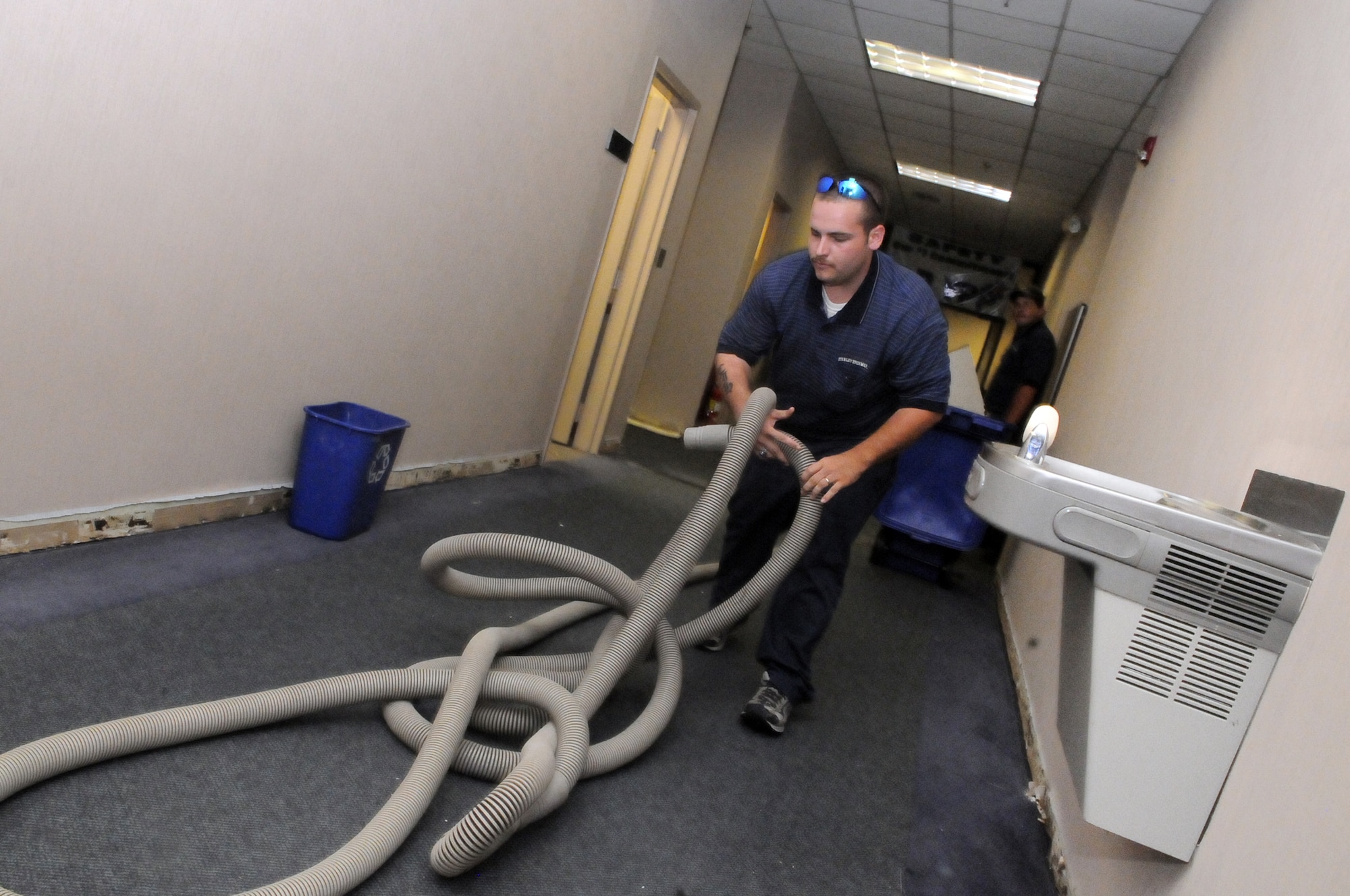 Cliff Hendrix with Stanley Steemer pulls vacuum hose through the hallway at Bldg. 376 for clean up. U. S. Air Force photo by Sue Sapp