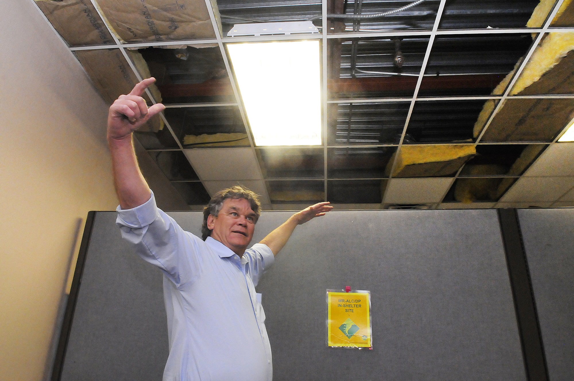 Mike Gavin points out where ceiling tiles and insulation are gone as a result of the water damage in building 376. U. S. Air Force photo by Sue Sapp