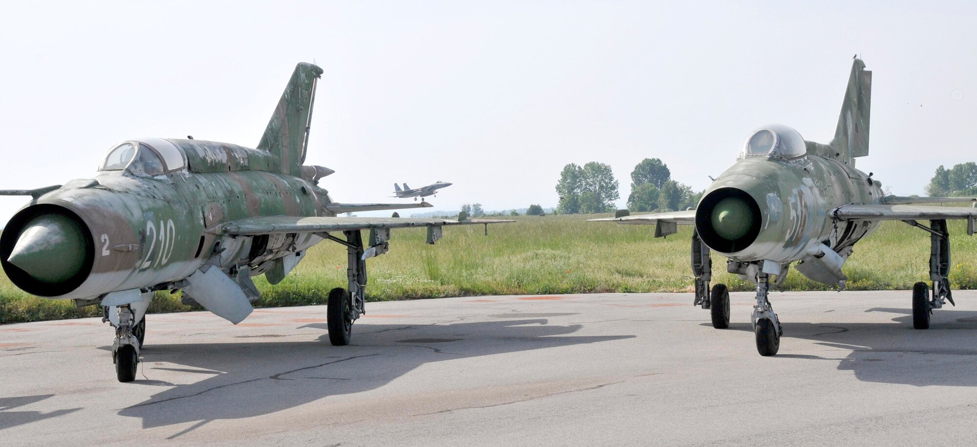 Two MiG-21s sit on the tarmac as an F-15 Eagle pilot lands May 13, 2010, at Graf Ignatievo Air Force Base in Plovdiv, Bulgaria. Airmen from the 48th Fighter Wing are in Bulgaria taking part in Sentry Gold, an exercise developed to familiarize U.S. pilots with the MiG airframes, build partnerships with the Bulgarian air force and assist them in their continued integration into NATO operations. The F-15 is from the 493rd Fighter Squadron at RAF Lakenheath, England. (U.S. Air Force/courtesy photo)
