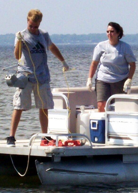 Melissa Hoover and Jordan Gibson of Brown, Burdine and Associates collect
sediment samples, from Choctawhatchee Bay, using a stainless steel Ponar sampling device. The base is collecting samples and documentation to establish a baseline condition of the 18 miles of Santa Rosa Island that Eglin controls along with the miles of shoreline along Choctawhatchee Bay to ensure the base has a strong understanding of its coastal natural resources.  (Photo by Jonathan Kramer.)
