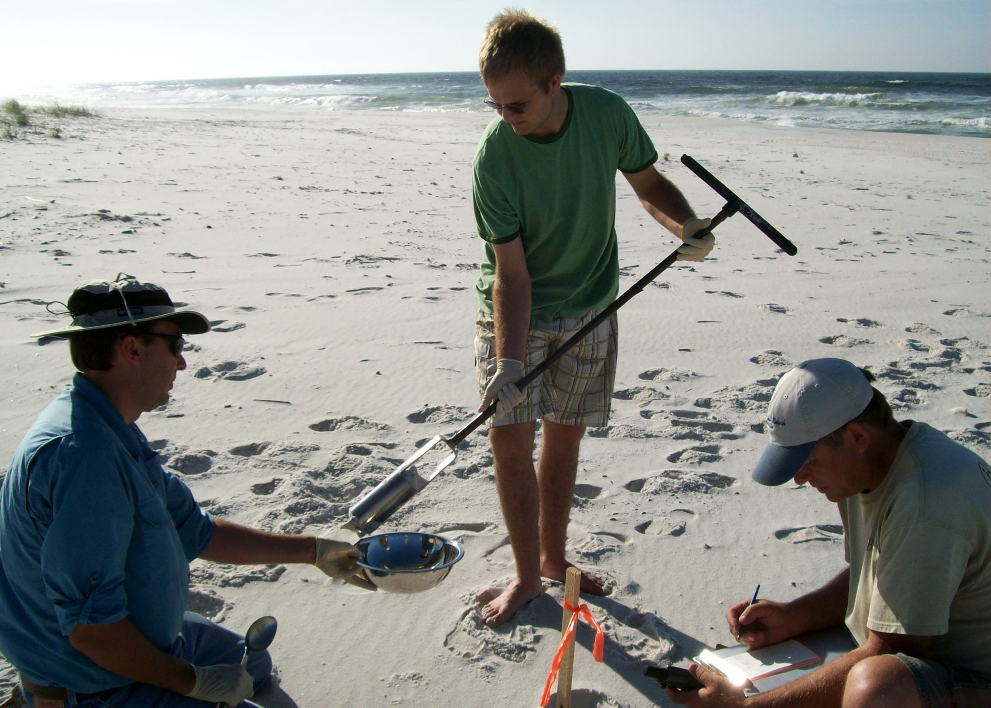 Jonathan Kramer, Jordan Gibson, and Tony Schmucker of Brown, Burdine and
Associates collect sand samples from Eglin property on Santa Rosa Island using a stainless steel hand auger. The base is collecting samples and documentation to establish a baseline condition of the 18 miles of Santa Rosa Island that Eglin controls along with the miles of shoreline along Choctawhatchee Bay to ensure the base has a strong understanding of its coastal natural resources.  (Photo by Casey Anderson.)
