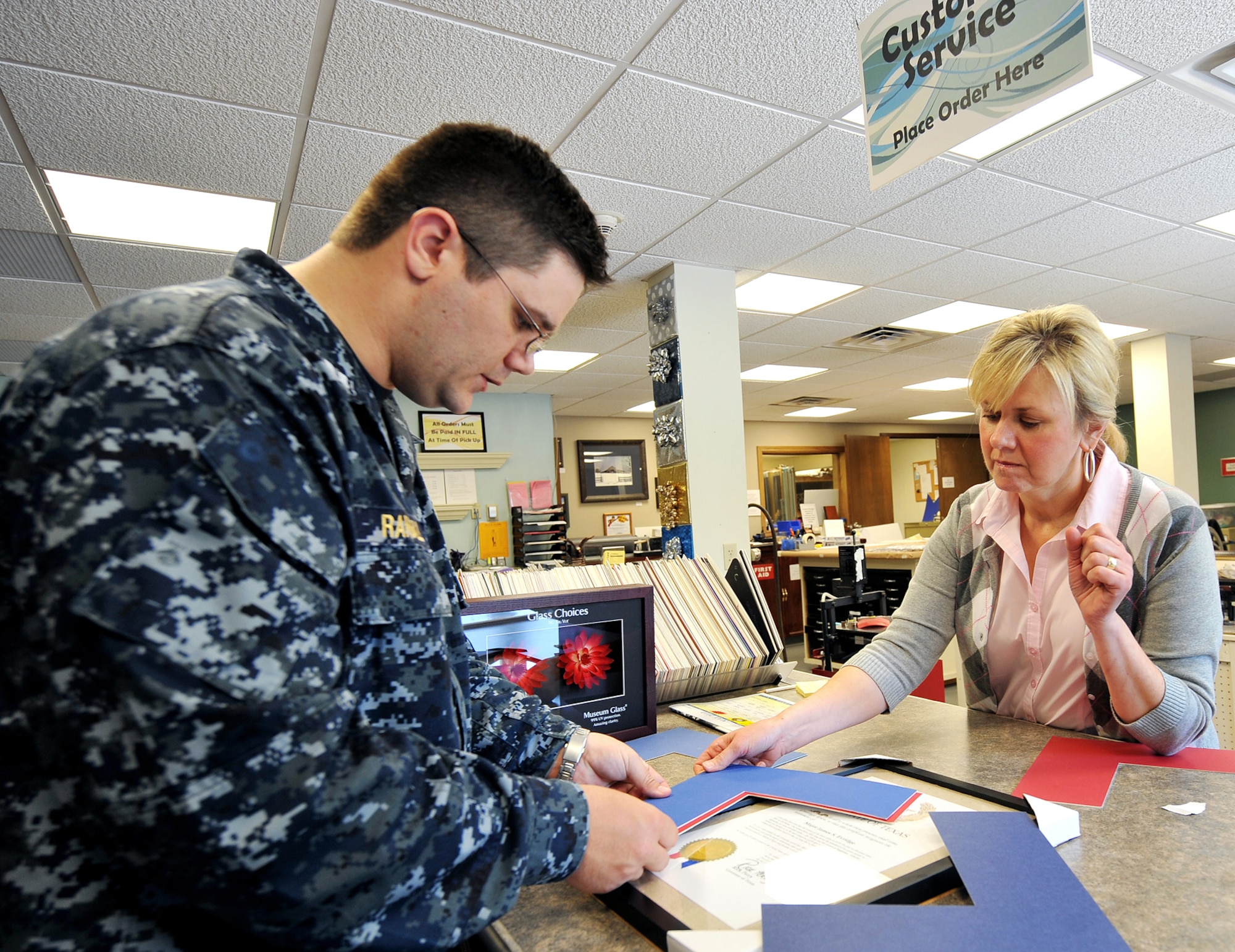 OFFUTT AIR FORCE BASE, Neb. -- Navy Lt. Jeremy Randall, U.S. Strategic Command, asks Katherine Krug, 55th Force Support Squadron, to help him find matte cardboard to use inside a frame at the Arts and Crafts Center here May 18. The facility offers pottery and stained glass classes and offers the Offutt community a place to obtain retail framing and engraving services. U.S. Air Force Photo by Charles Haymond