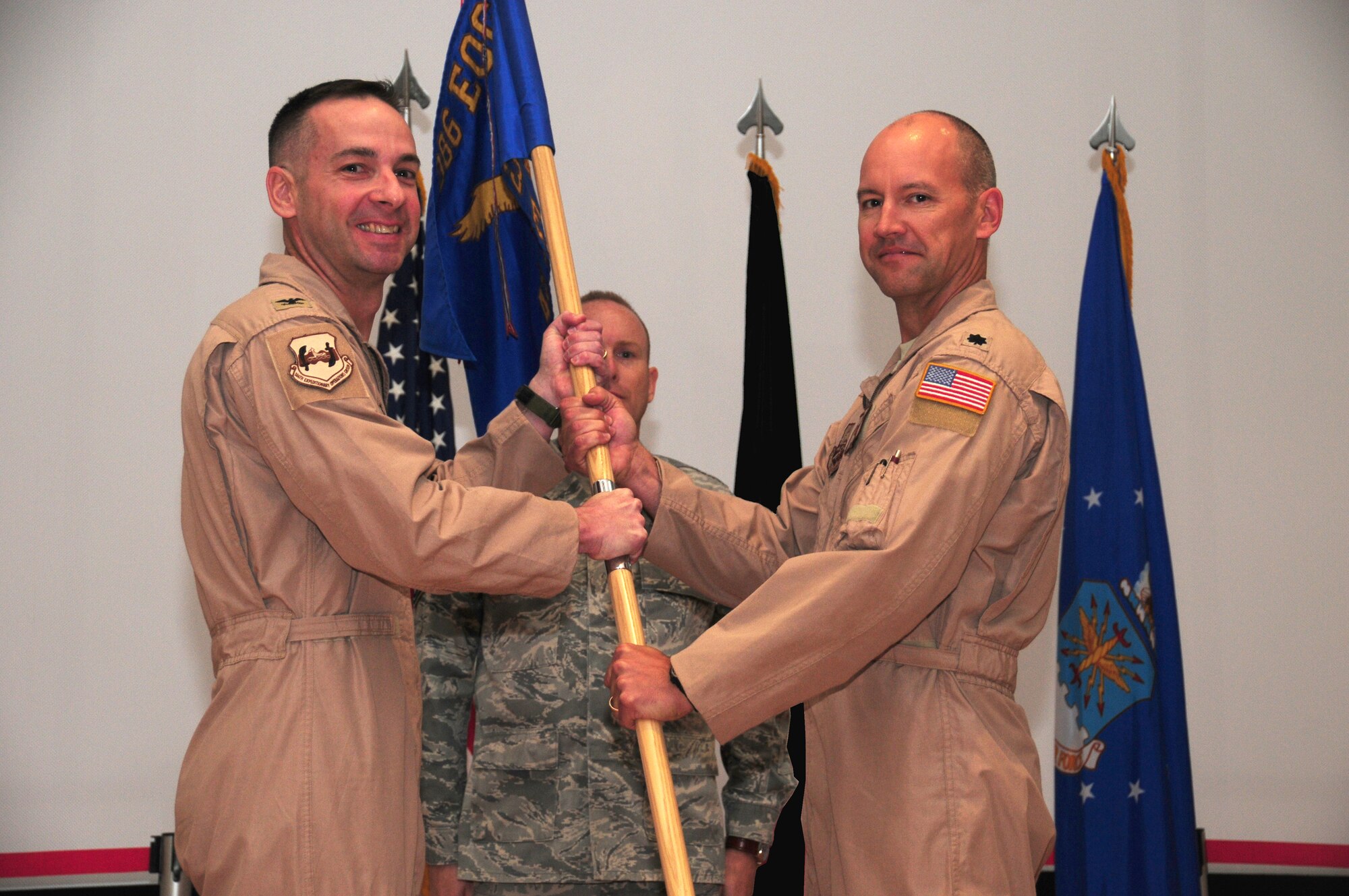 SOUTHWEST ASIA - From left, U.S. Air Force Col. Mark Czelusta, 386th Expeditionary Operations Group commander, passes the 43rd Expeditionary Electronic Combat Squadron guidon to Lt. Col. John Rye, the new 43rd EECS commander, upon his assumption of command during a ceremony here May 18, 2010 at the base theater. Colonel Rye assumed command after Lt. Col. John Reimer relinquished command. (U.S. Air Force photo illustration by Staff Sgt. Lakisha A. Croley/Released)