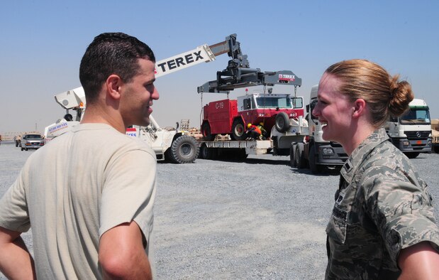 U.S. Air Force Staff Sgt. Joseph Jacovina and 1st Lt. Elise Jones, U.S. Air Forces Central Command liaison officers, discuss the movement of an Air Force fire truck while contractors load the asset onto a truck to be taken to the nearby sea port May 4, 2010 at an undisclosed location in Southwest Asia. Sergeant Jacovina and Lieutenant Jones coordinate sea-based shipments of oversized military equipment in and out of the USAFCENT area of responsibility. (U.S. Air Force photo by Staff Sgt. Lakisha A. Croley/Released)