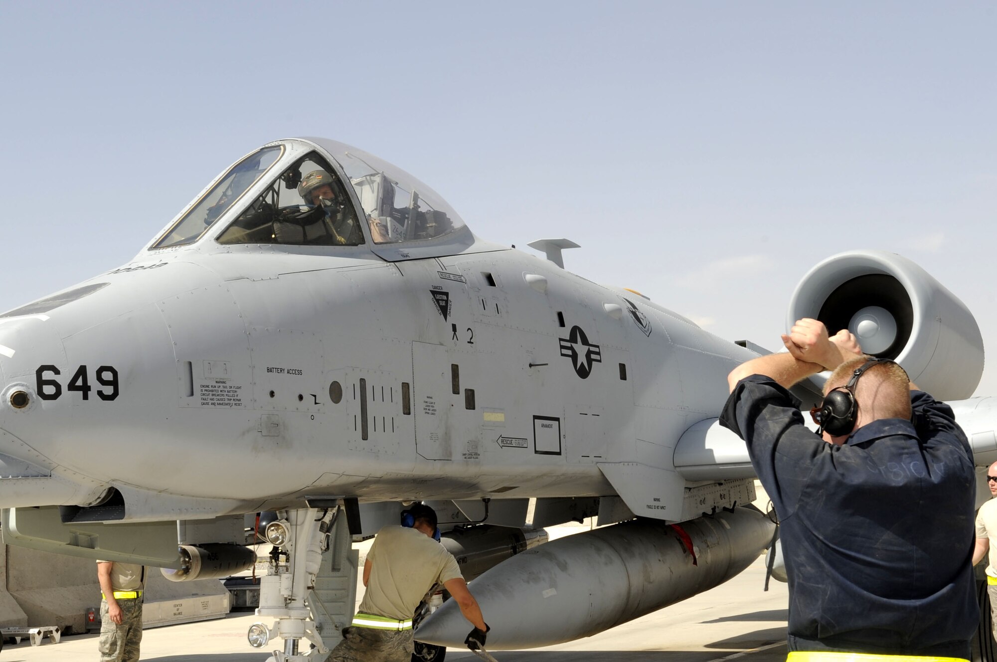 A crew chief from the 81st Expeditionary Aircraft Maintenance Squadron gives a signal for the A-10 Thunderbolt II pilot to hold his position as the chalks are put in place May 11 on Kandahar Airfield.  The crew chiefs are conducting post flight checks to make the jet ground safe.  (U.S. Air Force photo by Senior Airman Nancy Hooks/Released)