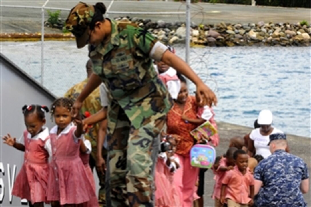 U.S. Navy Petty Officer 1st Class Tiffany Summers helps students from Brain-Shapers Academy board the High Speed Vessel Swift for a tour, Port Antonio, Jamaica, May 13, 2010. Swift is supporting Southern Partnership Station, a deployment of various specialty platforms to the U.S. Southern Command area of responsibility in the Caribbean and Latin America.