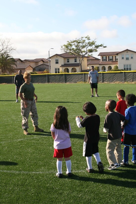 Sgt. Denise M. Serrano, the Combat Camera photography chief with Headquarters and Headquarters Squadron, lines up a soccer team of five year olds for a free kick at practice on field two of the Youth Sports Complex May 20. Serrano is a volunteer and the team's head coach.