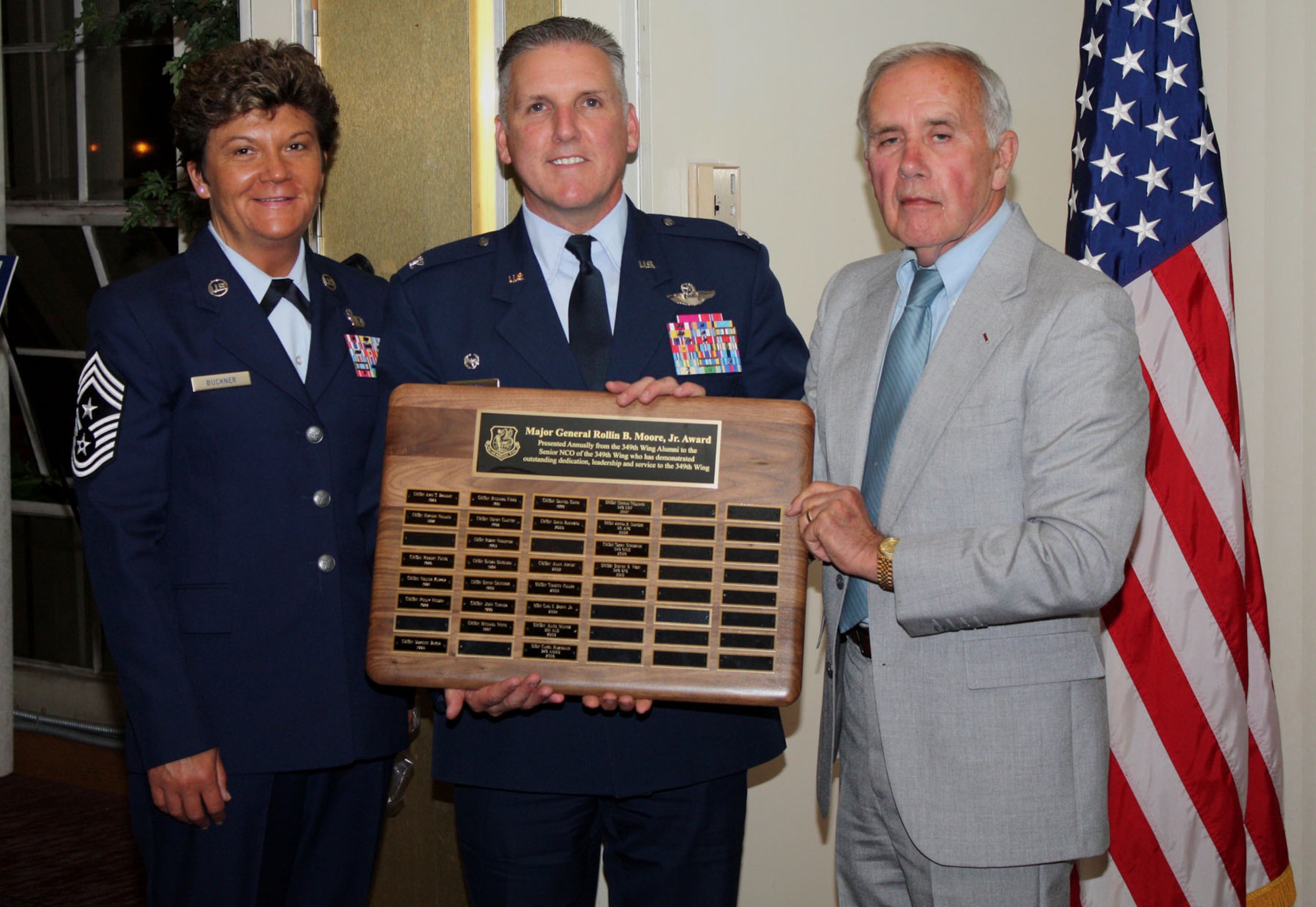 TRAVIS AIR FORCE BASE, Calif. -- Prior member of the 349th Air Mobility Wing, Brig. Gen. Richard K. Vogel (U.S. Air Force, Retired) presents a plaque to Col. John ‘Jay’ Flournoy, the 349th Air Mobility Wing commander, and Command Chief Master Sgt. Kathleen R. Buckner, listing all of the wings Maj. Gen. Rollin B. Moore Memorial Award recipients. The plaque was presented to the wing on behalf of the 349th Alumni Association at the Travis Conference Center during their annual banquet held recently.. The award was presented at the Travis Conference Center during the annual 349th Alumni Association dinner, May 15. The award is presented to the 349th Air Mobility Wing senior enlisted member who has demonstrated outstanding dedication and service to the wing mission. (U.S. Air Force photo/Master Sgt. Robert Wade)
