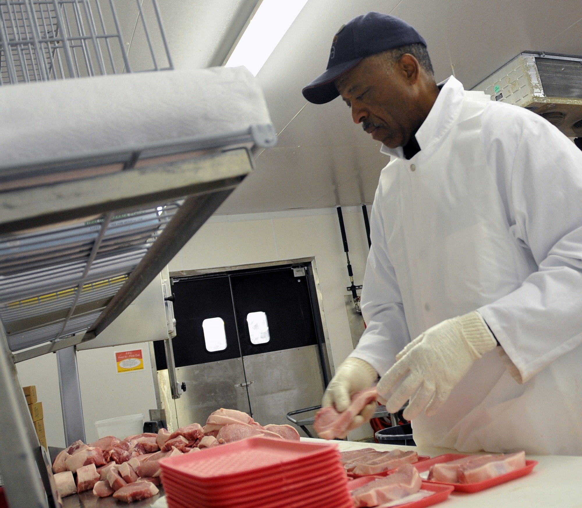 OFFUTT AIR FORCE BASE, Neb. -- Norvel Bryant, a commissary employee, trims fat from the edge of a piece of meat and prepares it for packaging in the Offutt Commissary's meat department May 20. The department recently took first place for best in merchandising at the 2nd Annual Defense Commissary Agency Meat Merchandising Contest. U.S. Air Force Photo by Jeff W. Gates