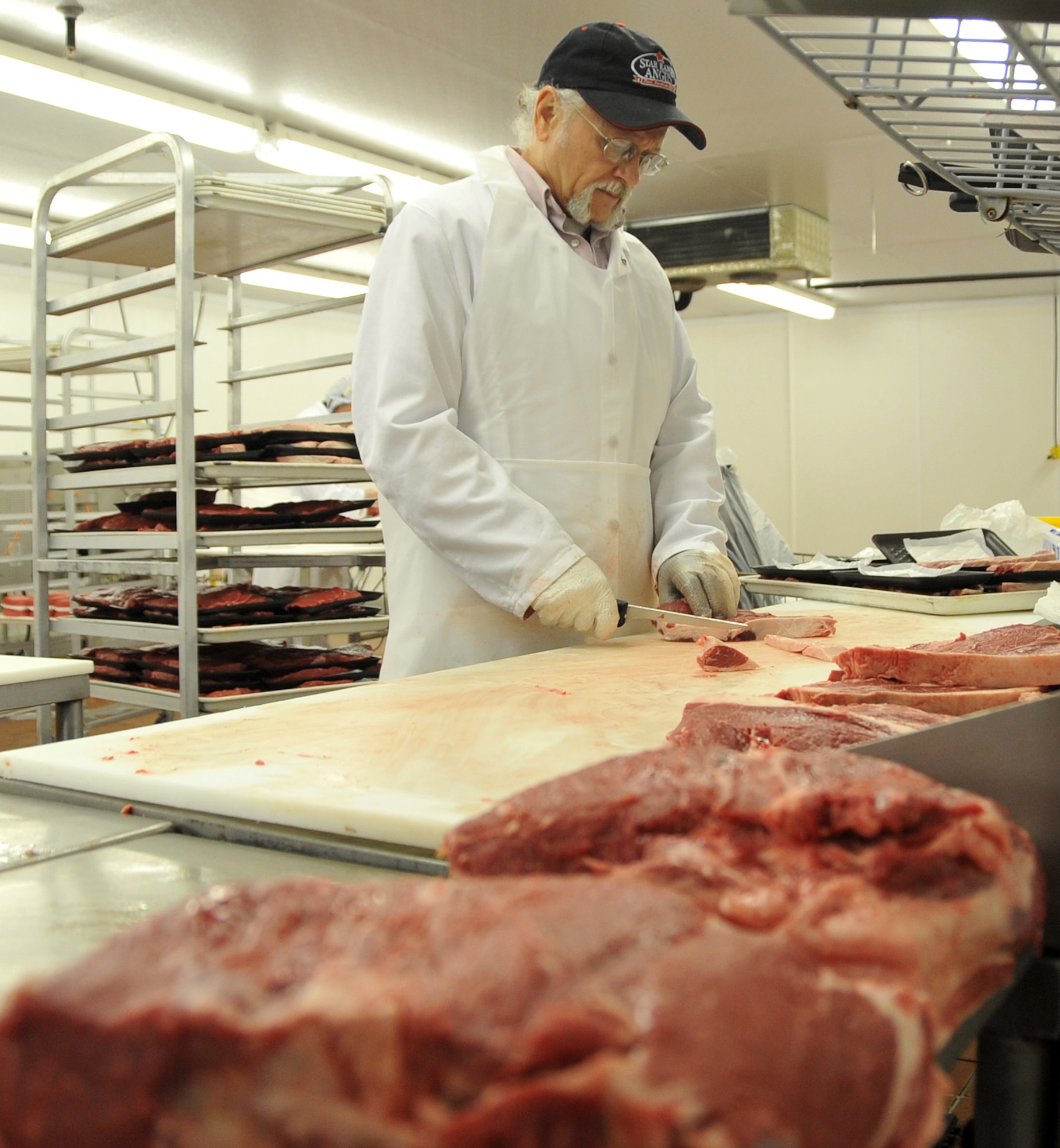 OFFUTT AIR FORCE BASE, Neb. -- Gary Foutch, a commissary employee, trims fat from the edge of a piece of meat behind the Offutt Commissary meat counter here May 20. The commissary's meat department recently took first place for best in merchandising at the 2nd Annual Defense Commissary Agency Meat Merchandising Contest. U.S. Air Force Photo by Jeff W. Gates