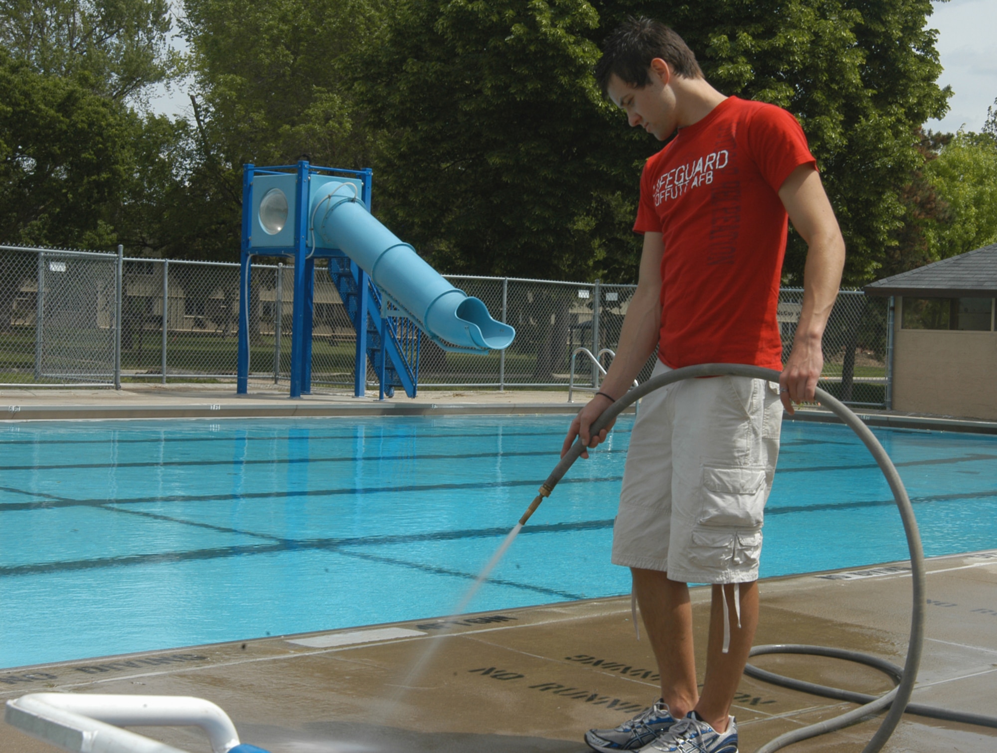 OFFUTT AIR FORCE BASE, Neb. -- Joe Weir, a lifeguard with the 55th Force Support Squadron, hoses down the deck of the base pool here May 19. Mr. Weir has been a lifeguard since he was 16 and has worked here for the past two years. He volunteered to help clean the pool to help prepare it for the summer season. The base and Capehart Pools open May 29. U.S. Air Force Photo by Staff Sgt. James M. Hodgman