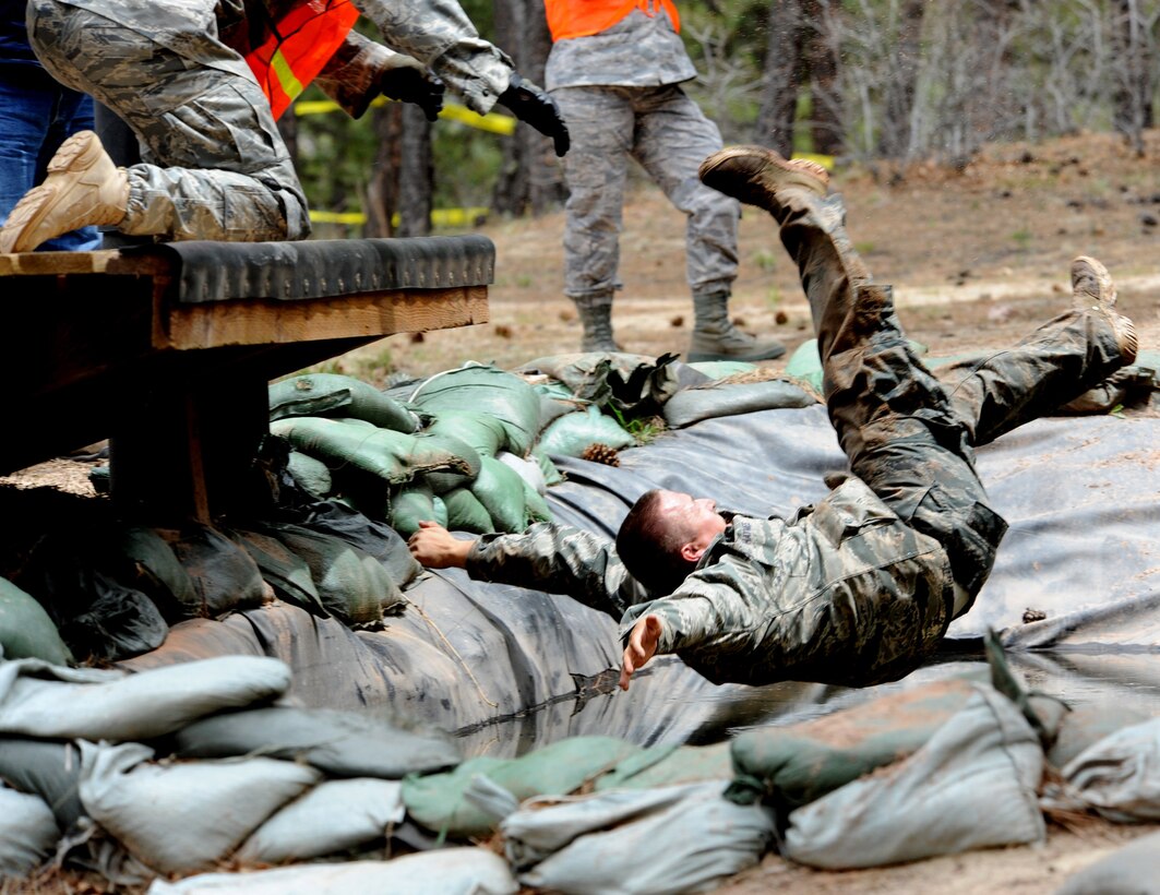 Department of Defense Officer Steven Haymes falls into the water right after completing his upside-down, hand-over-hand crossing on the rope at the Guardian Challenge 2010's obstacle course May 19 during the final portion of the security forces competition. Officer Haymes is a member from the Space and Missile Systems Center's 61st Security Forces Squadron. (Photo by Lou Hernandez)
