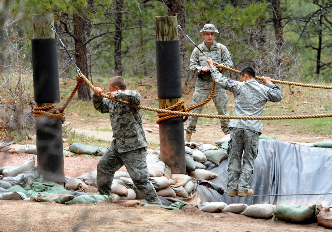 Department of Defense Officer Steven Haymes  (left) and Tech. Sgt. Rochanapan Silpe (right) hold onto the ropes while passing a water pond as an official looks on at the Guardian Challenge 2010's obstacle course May 19 during the final portion of the security forces competition. Both are members from the Space and Missile Systems Center's 61st Security Forces Squadron. (Photo by Lou Hernandez)