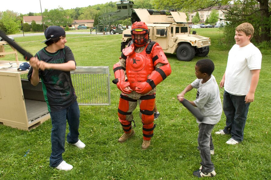 HANSCOM AIR FORCE BASE, Mass. - During Exhibition Day Joey Lewis, Nicolas Tucker and Raymond Merring  (l to r) demonstrate the "red man suit" and its ability to withstand abuse from potential rioters.  Lance Cpl. Christopher Richard, from the 25th Marines Division, wears the suit. The Security Forces Squadron had many items and equipment on display on May 12 for Exhibition Day as part of Police Week activities. (U.S. Air Force photo by Mark Wyatt)
