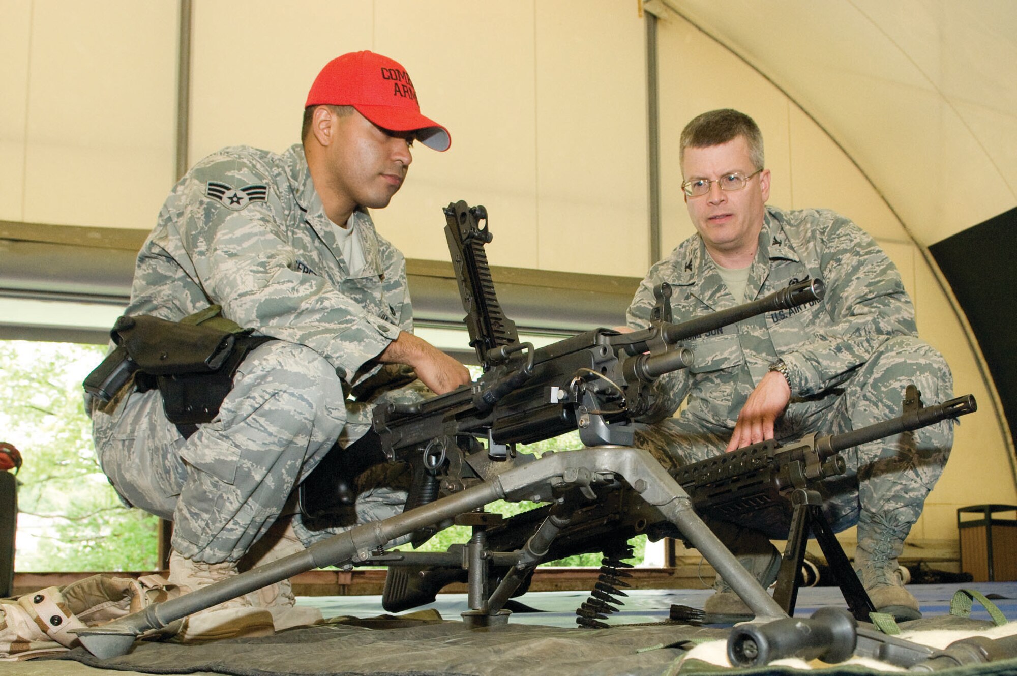 HANSCOM AIR FORCE BASE, Mass. – Senior Airman Alex Perez (l), 66th Security Forces Squadron, Combat Arms Training Maintenance, explains the capabilities of the M249 and the M240B on display to Col.  Charles F. Thompson, 66th Air Base Wing commander, in the Tennis Bubble. The Security Forces Squadron had many items and equipment on display on May 12 for Exhibition Day as part of Police Week activities. (U.S. Air Force photo by Mark Wyatt)