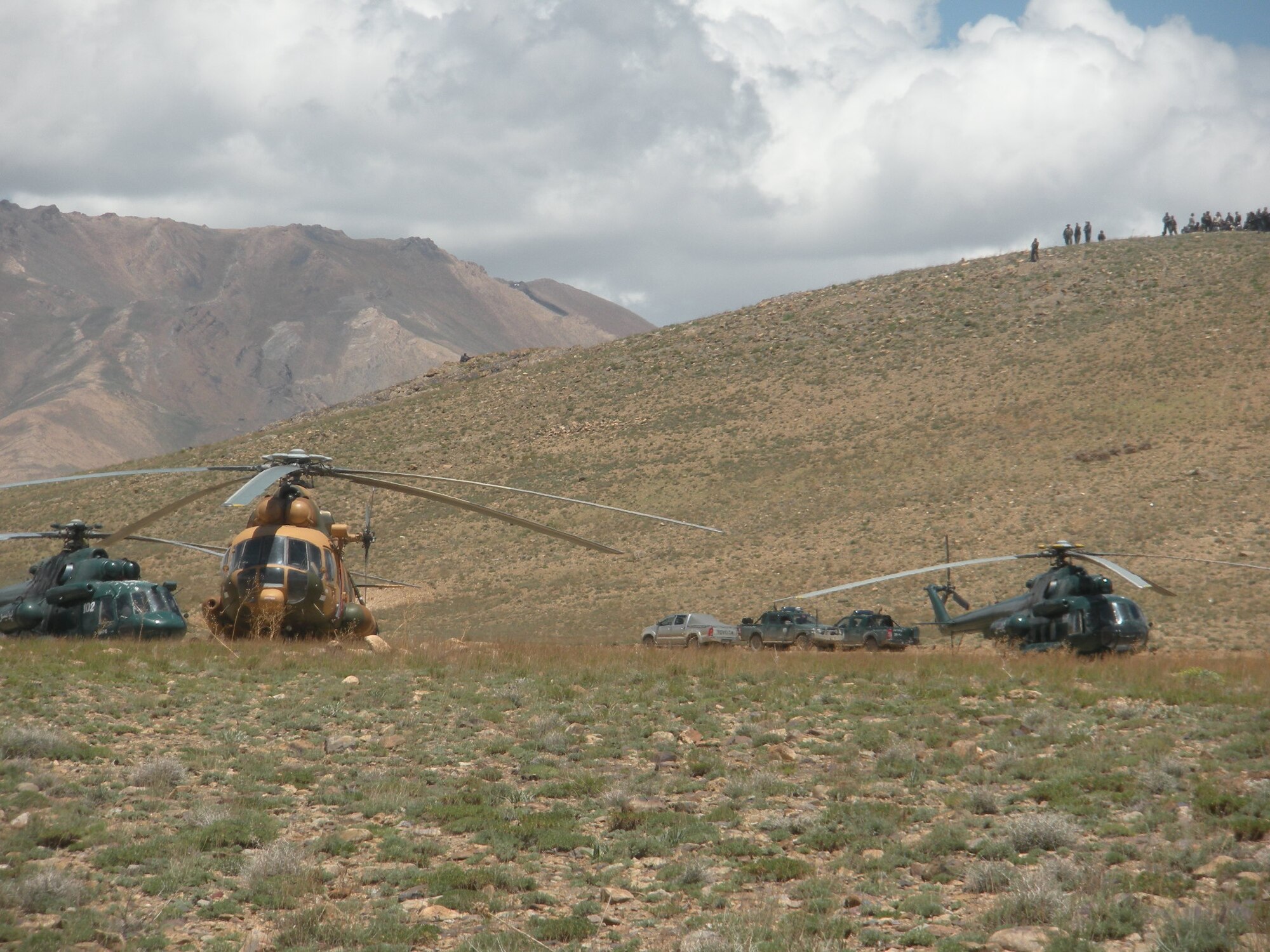 Afghan Air Corps and Air Interdiction Unit helicopters crews wait as government officials attend a peace jirga to settle a dispute between two large groups of Kochi and Hazara citizens May 18, 2010, in Daimerdad, Afghanistan. (U.S. Military photo/RELEASED)